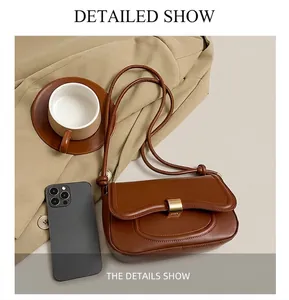 Detailed comparison showing compact size of brown leather underarm bag next to a smartphone