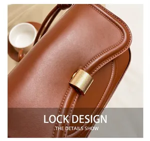 Detail of the golden metal bar lock and fine stitching on the brown leather shoulder bag