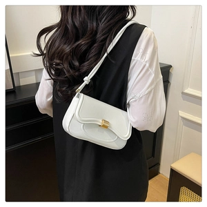 Detailed view of a white rectangular shoulder bag with gold buckle on a model in minimalist room