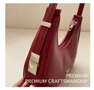 Détail du sac à bandoulière bordeaux avec logo nœud argenté et boucle métallique