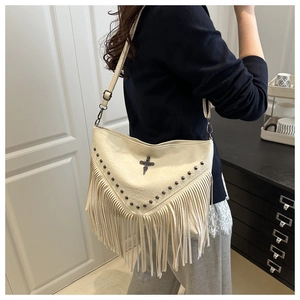Fashionable beige fringe crossbody bag with metal rivets and cross charm detail