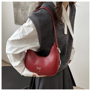 Detail of dark red crescent hobo bag featuring a silver metal bow on leather