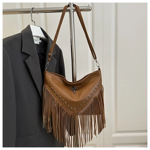 Detail of brown fringe crossbody bag with silver studs and metal cross pendant