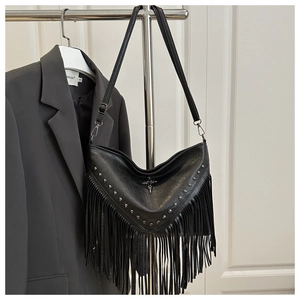 Detail of black fringe leather bag featuring silver studs and vintage cross ornament