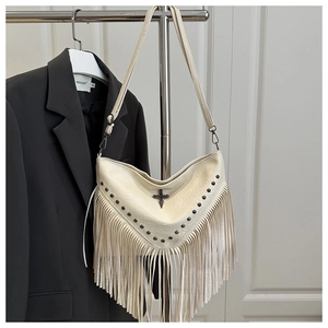 Detail of cream tassel shoulder bag with metallic cross pendant and silver rivet studs