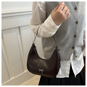 Détail du sac sous l'aisselle en cuir marron foncé avec un nœud en métal argenté