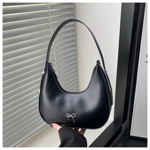 Detail of a black crescent shoulder bag featuring a decorative silver bow metal accent