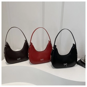 Détail de sacs hobo en marron, rouge et noir avec des ornements de nœuds argentés