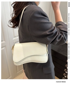 Detail view of cream white underarm bag with irregular wave flap on grey blazer