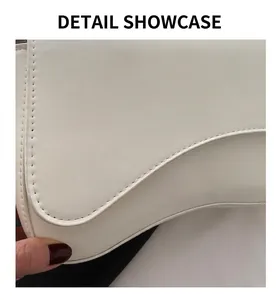 Detail shot of white leather saddle bag showing precise stitching and curved flap design