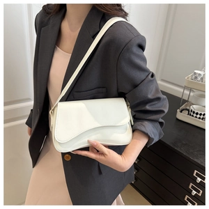 Chic white saddle bag with wavy flap design styled on a model in a gray suit