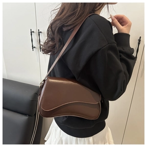 Close-up of a dark brown leather shoulder bag with a modern asymmetrical flap design