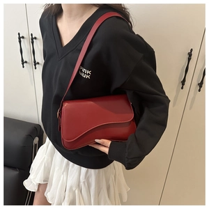 Detail of the chic burgundy leather handbag showing the unique asymmetric geometric flap