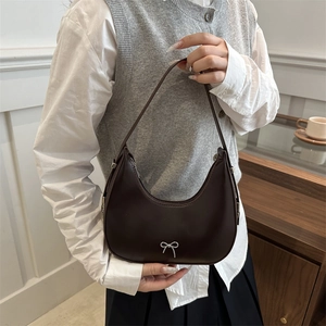 Deep brown crescent hobo bag with silver bow detail worn by model in minimalist outfit