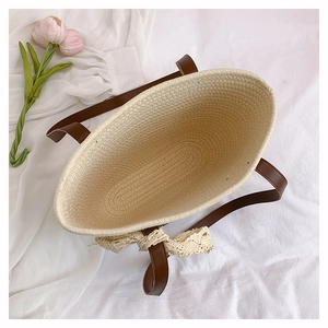 Top view of woven tote bag showing inner space, leather handles and lace bow detail