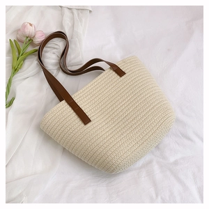 Close-up of cream woven tote bag with brown leather handles and pink tulip detail