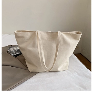Detailed close-up of the natural woven canvas texture on a large minimalist beige tote bag