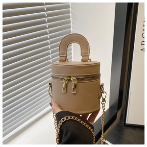 Détail d'un sac seau beige avec double fermeture éclair et bandoulière dorée