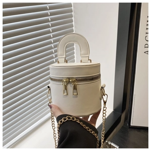 Détail d'un mini sac seau blanc cylindrique avec double fermeture éclair dorée et chaîne