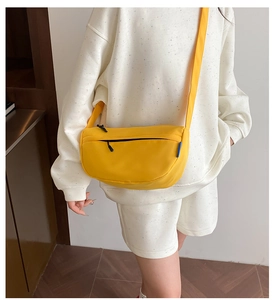 Detail of adjustable shoulder strap and zipper closure on yellow nylon half-moon bag