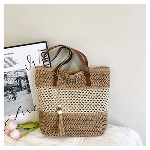 Detail of color-block woven tote bag with leather handle and decorative tassel