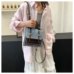Model wearing a vintage contrast crossbody bag in blue denim and brown leather