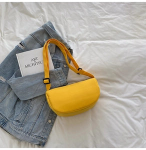Macro detail of the bright yellow crescent nylon bag on a white sheet with a book