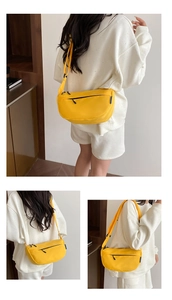 Detail view of a yellow half-moon crossbody bag with black zipper and adjustable strap