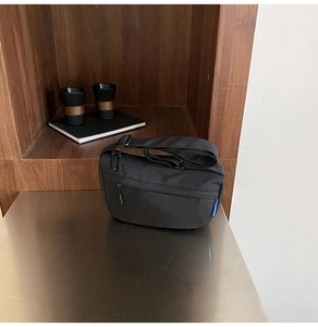 Detail of black crescent crossbody bag with zipper pocket and adjustable strap on a metal table