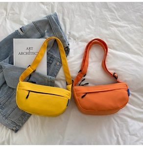 Detail of yellow and orange nylon crescent bags with adjustable straps on white linen