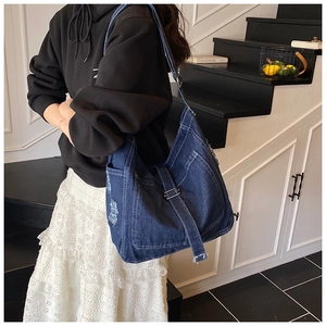 Detail of dark blue denim tote with white stitching and silver metal buckle strap