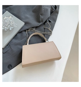 Detail of light beige trapezoid handbag with sparkling rhinestone handle and silver chain