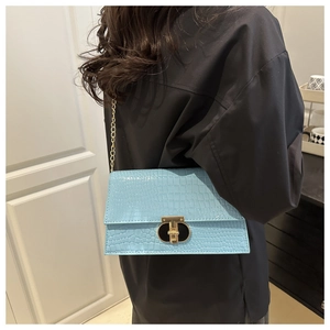 Detail of light blue crocodile embossed leather shoulder bag with golden chain and clasp