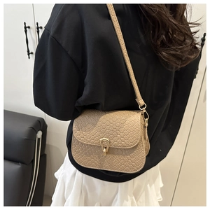 Dettaglio borsa a tracolla intrecciata beige con fibbia dorata sulla spalla