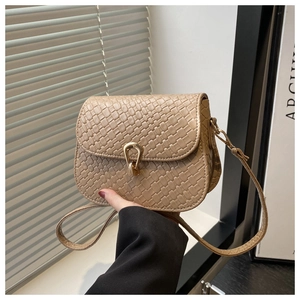 Detail of beige woven square bag with golden horseshoe metal lock and leather strap