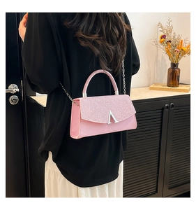 Detail of pink glitter flap bag with silver V-shaped buckle and metal chain strap