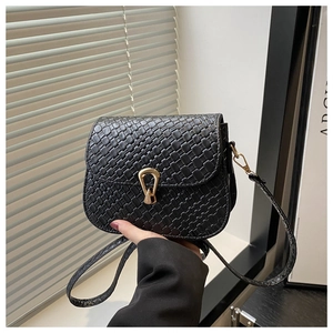 Detail of black woven texture handbag featuring a golden horseshoe metallic lock closure