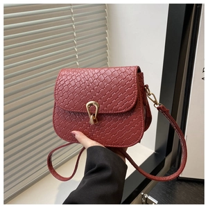 Handheld shot of brick red woven leather small square bag with golden horseshoe lock