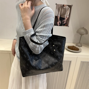 Black leather tote bag with cartoon bear print and golden rivets in a lifestyle scene