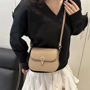 Minimalist beige woven crossbody bag with golden horseshoe clasp and slim strap