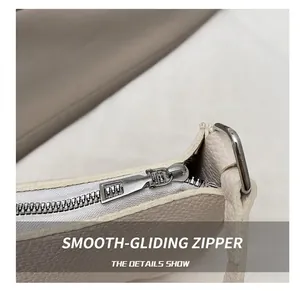 Detail of smooth silver zipper and pebbled texture on a beige faux leather handbag