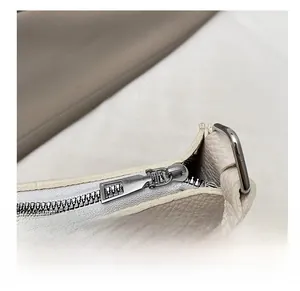 Detail of smooth silver zipper and pebbled texture on a beige faux leather handbag