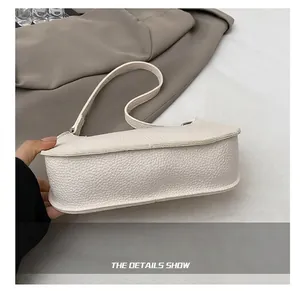 Close-up of the wide reinforced bottom and lychee grain texture of the white baguette bag