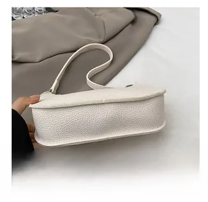 Close-up of the wide reinforced bottom and lychee grain texture of the white baguette bag