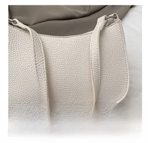 Close-up of beige lychee-textured leather shoulder bag with silver metal buckles
