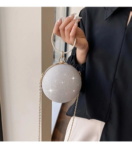 Detail showing the silver sequined spherical clutch with a gold diamond-set ring handle