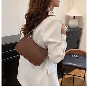 Detailed side view of a dark brown lychee leather shoulder bag on a female model