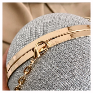 Detail of silver glitter spherical evening bag with gold metal frame and chain link clasp