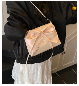 Macro detail of soft pink ribbon bow on pleated cloud bag with elegant leather chain strap