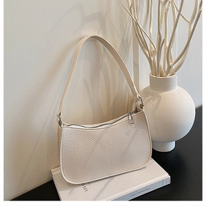 Detailed macro view of white lychee pattern leather texture on minimalist baguette bag